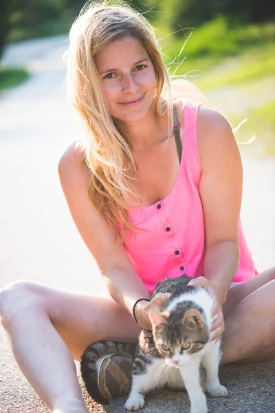 Jovem mulher loira brincando com gato ao ar livre — Fotografia de Stock