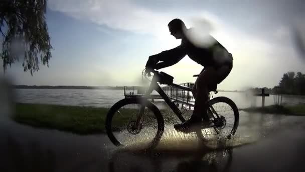 雨の日没、スローモーションで自転車に乗る — ストック動画