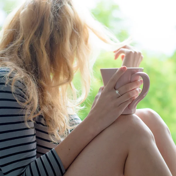 金髪の女性が庭でコーヒーを飲む — ストック写真