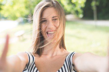 Beautiful young woman making selfie and grimacing