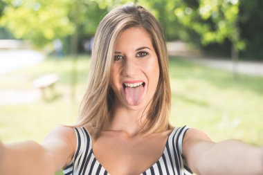 Beautiful young woman making selfie and grimacing