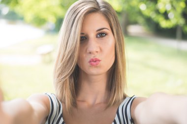 Beautiful young woman making selfie and grimacing