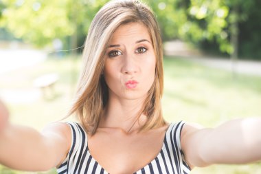 Beautiful young woman making selfie and grimacing