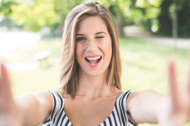 Beautiful young woman making selfie and grimacing