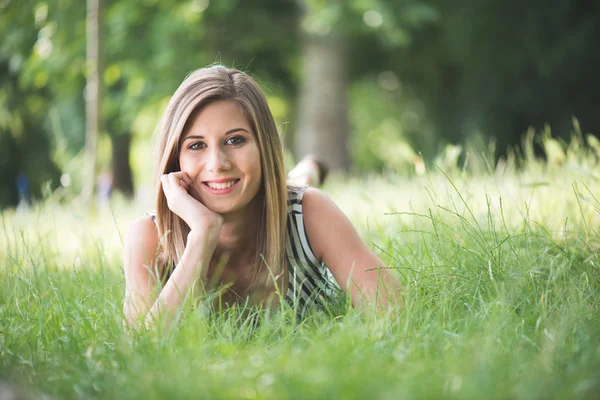 Lächelnde schöne Frau, die auf Gras liegt — Stockfoto