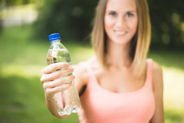 Beautiful young fitness woman holding water after working out — Stock Photo, Image