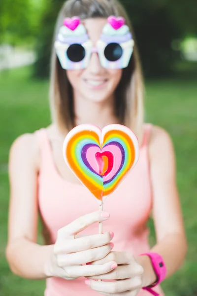 Teenage girl hiding behind lollipop — Stock Photo, Image