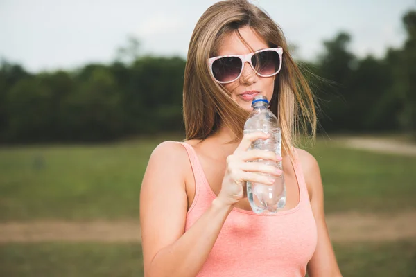 Jonge vrouw die water drinkt na inspanning — Stockfoto