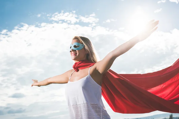 Junge Frau posiert als Superheldin über blauem Himmel — Stockfoto