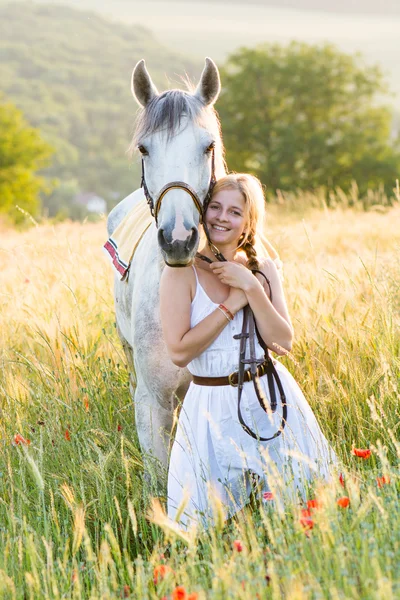 Jovem de pé com um cavalo branco ao ar livre — Fotografia de Stock