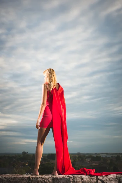 Mujer rubia en traje rojo observando el paisaje — Foto de Stock