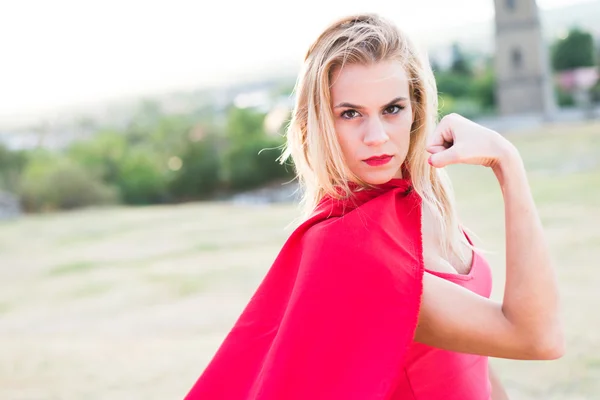 Mulher loira confiante em traje vermelho mostrando músculo e força — Fotografia de Stock