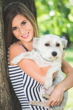 Young cute woman posing with her dog outdoor in the park