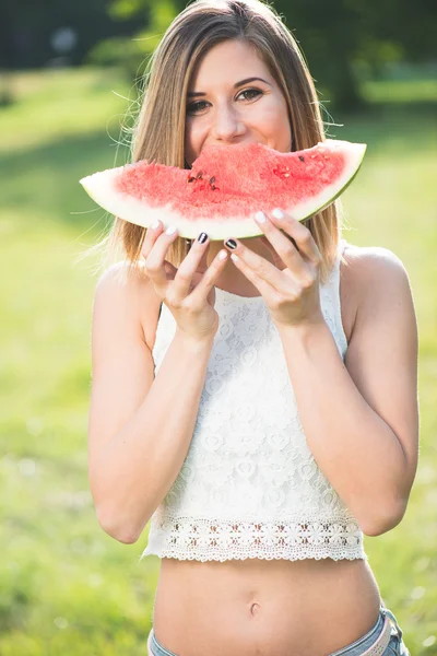 Young blonde woman eating fresh, juicy watermelon — Stok fotoğraf