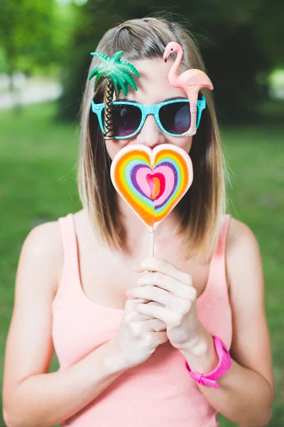 Beautiful young woman is holding lollipop in front of her mouth while standing — Stock Photo, Image