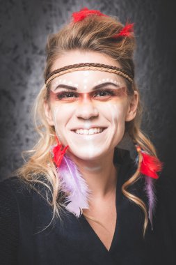 American Indian with paint face camouflage, smiling and looking into camera - studio photo with professional makeup