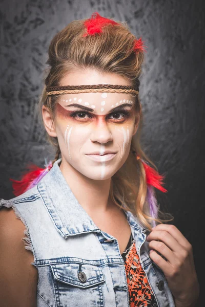 American Indian with paint face camouflage, smiling and looking into camera - studio photo with professional makeup
