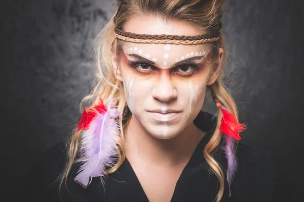 American Indian with paint face camouflage, smiling and looking into camera - studio photo with professional makeup — Stok fotoğraf