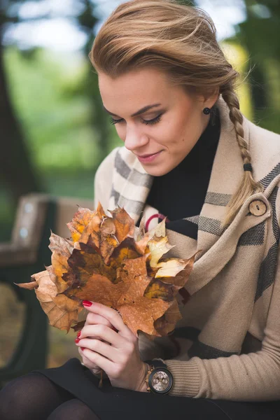 Frau hält Herbstlaub in der Hand — Stockfoto
