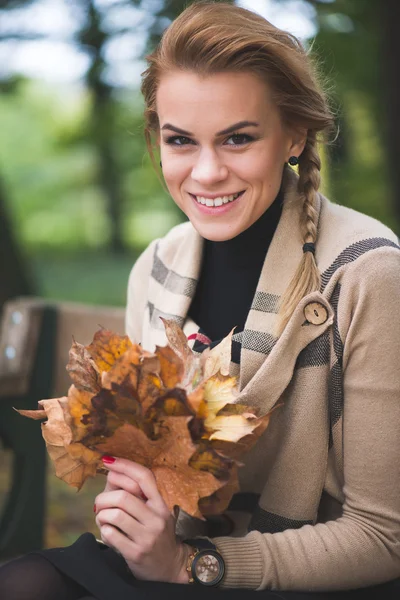 Frau hält Herbstlaub in der Hand — Stockfoto