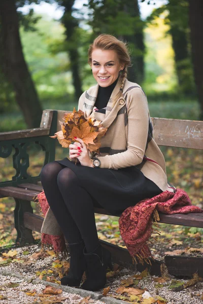 Blonde young woman holding autumn leaves — Stock Photo, Image