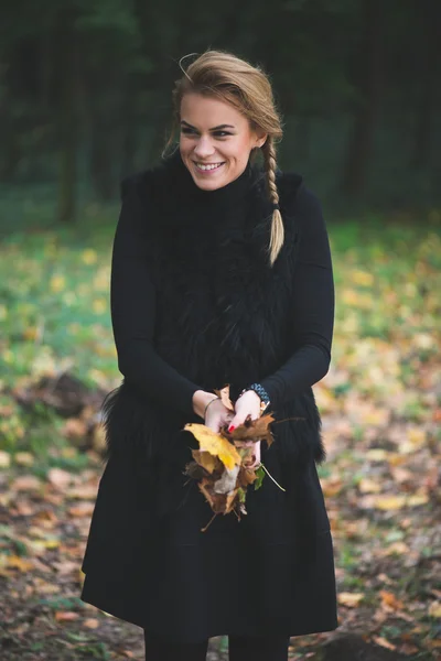 Mujer joven rubia sosteniendo hojas de otoño —  Fotos de Stock