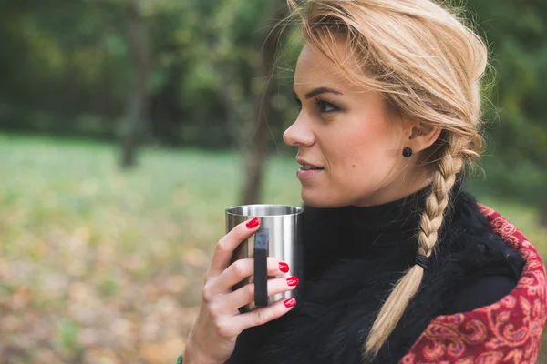 秋の公園で熱いお茶や屋外のコーヒーを飲む若い女性 — ストック写真