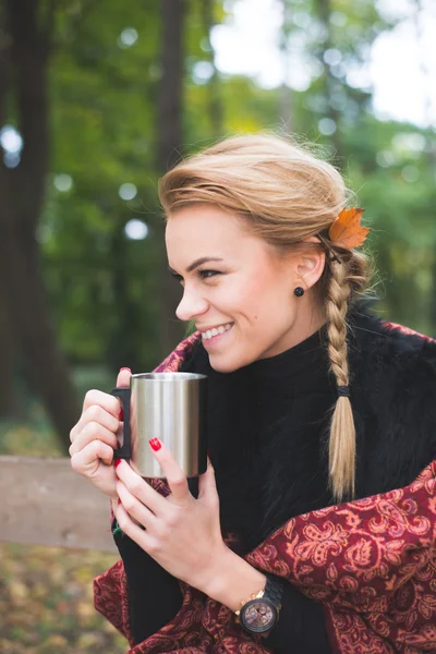 Junge Frau trinkt heißen Tee oder Kaffee im Freien im Herbstpark — Stockfoto