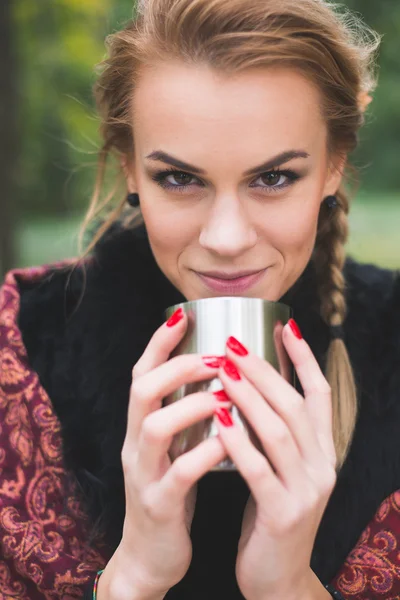 Νεαρή γυναίκα πίνοντας ζεστό τσάι ή καφέ υπαίθρια στο πάρκο φθινόπωρο — Φωτογραφία Αρχείου