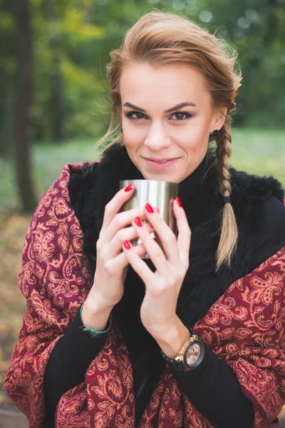 Νεαρή γυναίκα πίνοντας ζεστό τσάι ή καφέ υπαίθρια στο πάρκο φθινόπωρο — Φωτογραφία Αρχείου