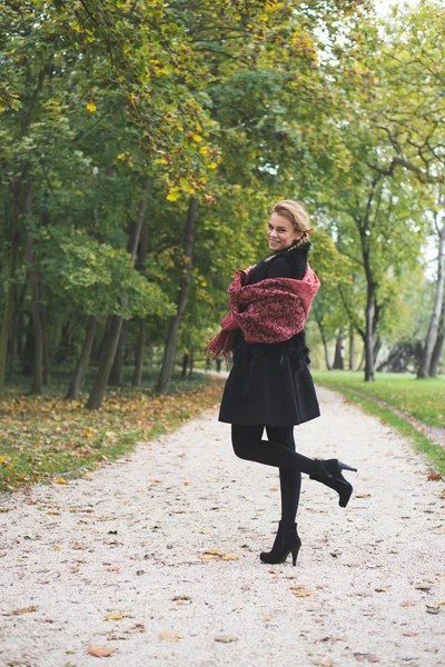 Elegant young woman standing in autumn park outdoor — Stock Photo, Image