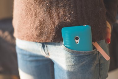 Hipster girl with smartphone in pocket