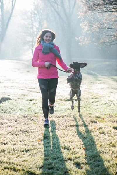 Runner vrouw en haar schattige Duitse aanwijzer hond samen uitgevoerd buiten op het mooie park. — Stockfoto