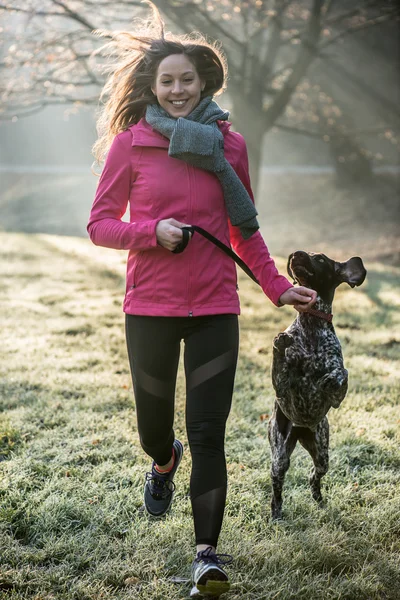 Runner mulher e seu bonito cão ponteiro alemão correndo juntos ao ar livre no belo parque . — Fotografia de Stock