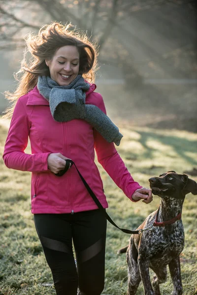 Runner mulher e seu bonito cão ponteiro alemão correndo juntos ao ar livre no belo parque . — Fotografia de Stock