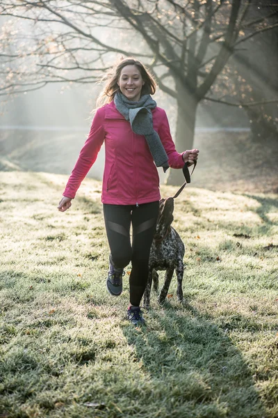 Runner mulher e seu bonito cão ponteiro alemão correndo juntos ao ar livre no belo parque . — Fotografia de Stock