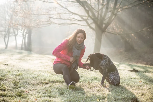 Donna e il suo cane che si allungano all'aperto. Fitness ragazza e il suo animale domestico lavorando insieme . — Foto Stock