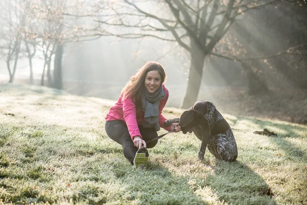 Kvinna och hennes hund sträcker sig utomhus. Fitness flicka och hennes husdjur träna tillsammans. — Stockfoto