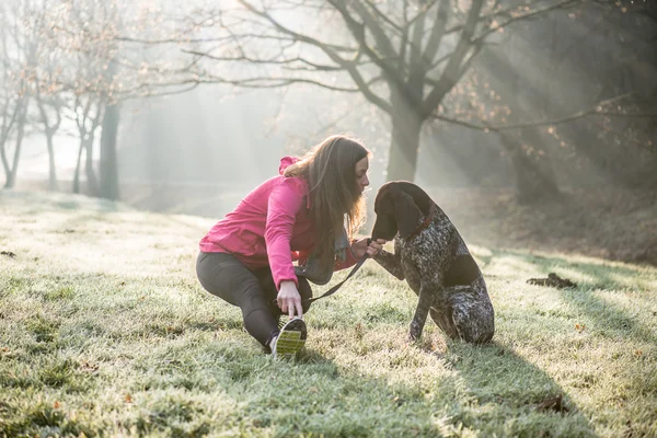 Donna e il suo cane che si allungano all'aperto. Fitness ragazza e il suo animale domestico lavorando insieme . — Foto Stock