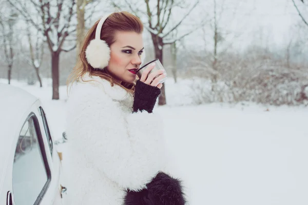 Junge Frau trinkt heißen Tee oder Kaffee im Freien, vintage Winterurlaub Konzept — Stockfoto