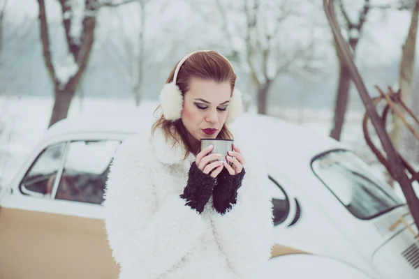Fiatal nő iszik forró teát vagy kávét kültéri, vintage téli vakáció koncepció — Stock Fotó