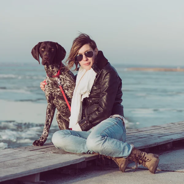Belle jeune femme jouant avec chien sur le rivage de la mer — Photo