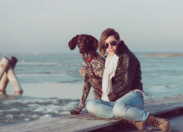 Vacker ung kvinna leker med hunden på havsstranden — Stockfoto