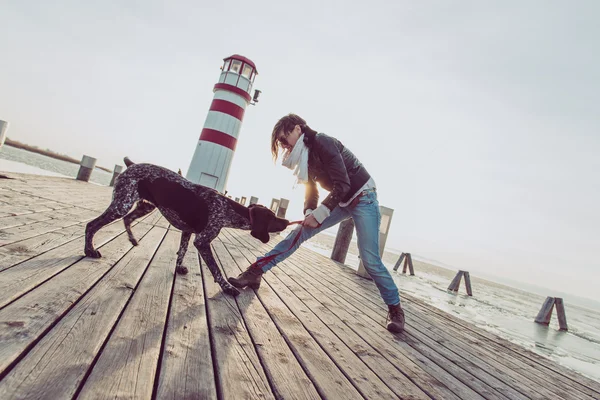 Bela jovem mulher brincando com o cão na costa do mar — Fotografia de Stock