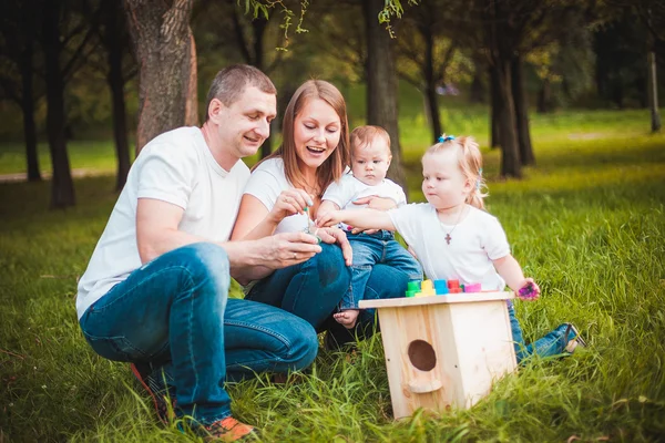 Família feliz com caixa de nidificação e tintas — Fotografia de Stock