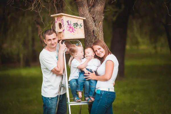 Família feliz com casa de pássaro de madeira — Fotografia de Stock