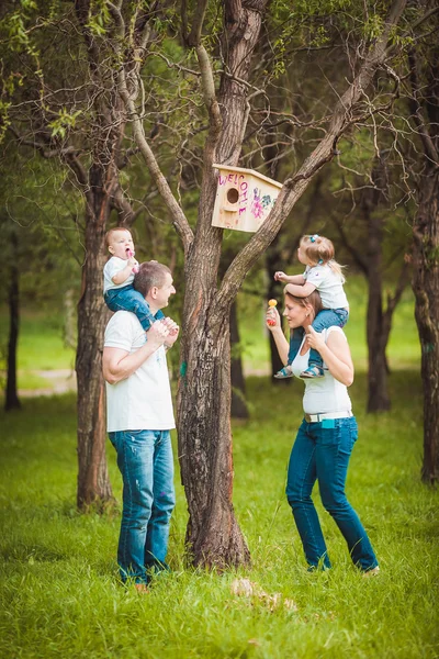 Família feliz com casa de pássaro de madeira — Fotografia de Stock