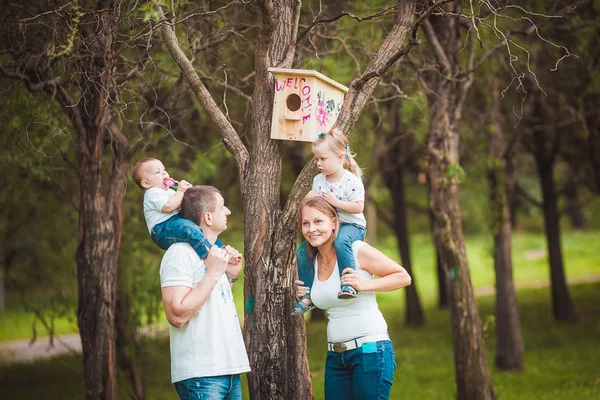 Família feliz com casa de pássaro de madeira — Fotografia de Stock