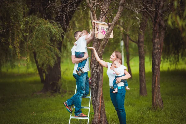 Família feliz com casa de pássaro de madeira — Fotografia de Stock