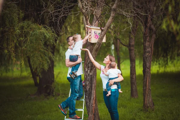 Família feliz com casa de pássaro de madeira — Fotografia de Stock